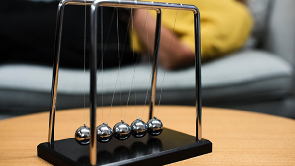 Newton cradle silver balance balls representing business cause and effect