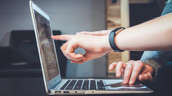 Business professional pointing at laptop screen for data review