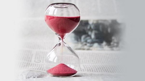 Pink hourglass on desk representing time management and deadlines